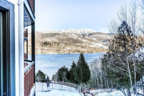 a window of a house with a view of a lake at Chic Mt-Tremblant Condo with View on the Lake by Denstays in Mont-Tremblant