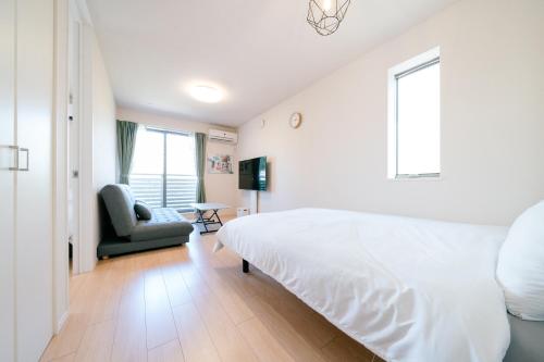 a white bedroom with a bed and a chair at Simple Stay Minoshima セルフチェックイン in Fukuoka