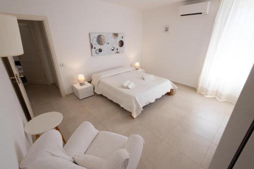 a white room with a bed and two chairs at Villa delle Muse in Marsala