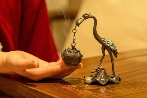 a person holding a toy bird on a table at Honglu Garden Hotel Bell and Drum Tower Huimin Street Store & 2 bottles of beer for free in Xi'an