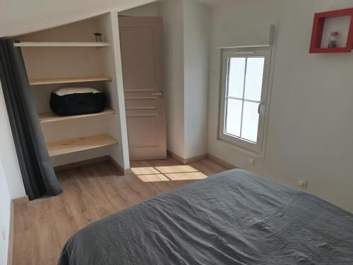 une chambre avec un lit et un placard avec une fenêtre dans l'établissement Maison Duplex, à Pierrelatte