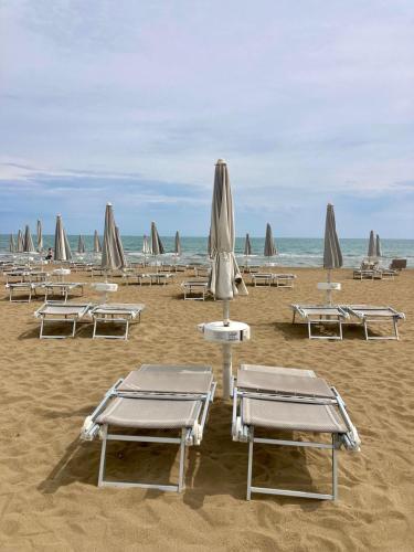 a beach with lounge chairs and umbrellas on the sand at Hotel Ivana in Lido di Jesolo