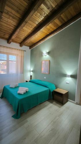 a bedroom with a green bed and a wooden ceiling at L'Ulivo Affittacamere Gonnosfanadiga in Gonnosfanàdiga