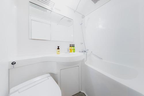 a white bathroom with a sink and a mirror at HOTEL MYSTAYS Miyazaki in Miyazaki