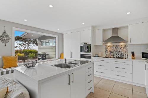 a kitchen with white cabinets and a sink at Sea views at Spring Beach Tasmanias East Coast in Spring Beach