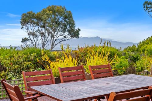 a wooden table and chairs with a view of the mountains at Sea views at Spring Beach Tasmanias East Coast in Spring Beach