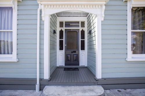 a blue house with a white door and a porch at Villa Retreat in Masterton