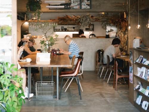 a group of people sitting at tables in a restaurant at Hostel Niniroom in Kyoto
