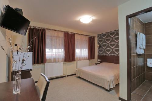 a bedroom with a bed and a table and a television at Prenociste Knez in Sombor