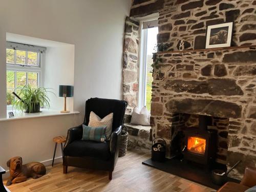 ein Wohnzimmer mit einem Steinkamin und einem Stuhl in der Unterkunft Waterfront cottage Applecross Peninsula in Ardheslaig