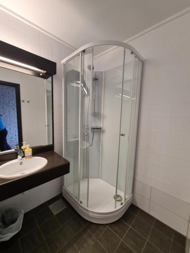 a bathroom with a shower and a sink at SKAP Hostel Mandal in Mandal