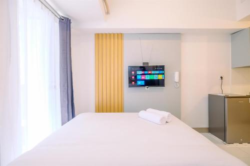 a bedroom with a white bed and a tv at Well Furnished and Restful Studio Tokyo Riverside PIK 2 Apartment By Travelio in Rawalembang