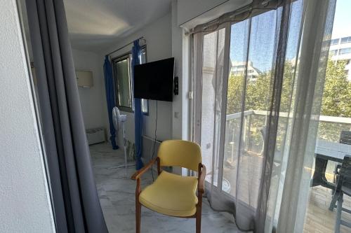 une chaise jaune dans une chambre avec fenêtre dans l'établissement Beautiful renovated T2 - close to the beach, à La Grande Motte