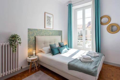 une chambre avec un lit avec des oreillers bleus et une fenêtre dans l'établissement #57 Suite Notre Dame Central balcony & AC, à Nice
