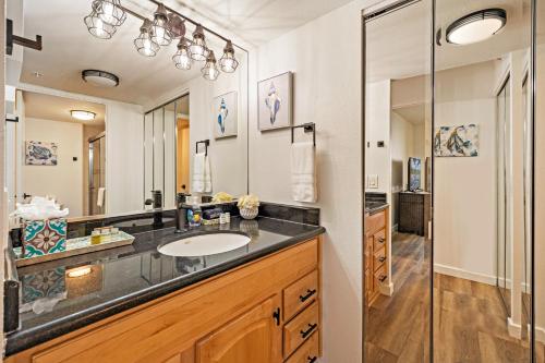 Un baño con lavabo y un espejo grande. en Mahana 718, en Kahana