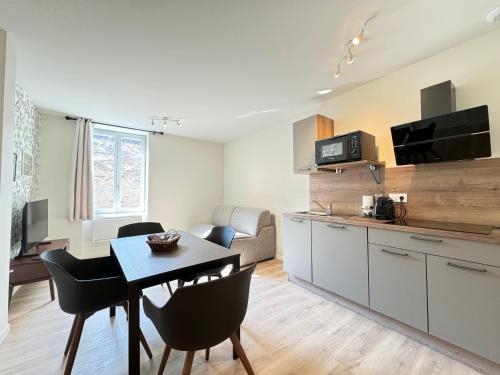 une cuisine et un salon avec une table et des chaises dans l'établissement Appartement Neuf pour 4 Personnes au Cœur de Riom N6, à Riom