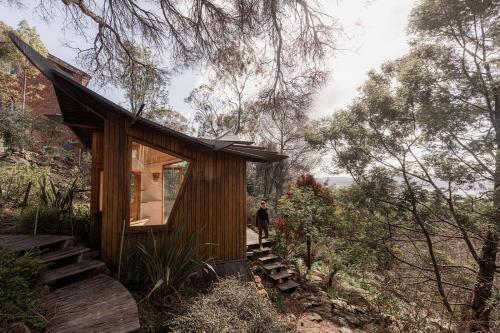 a person standing outside of a small wooden house at The Bends House in Sandy Bay