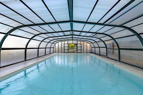une piscine intérieure avec un plafond en verre dans l'établissement Domaine la Noyeraie Périgord Noir, à Paulin