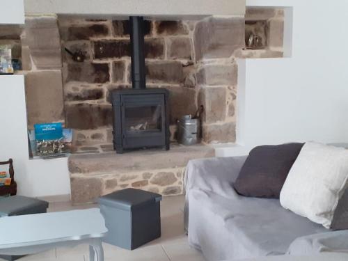 a living room with a stone fireplace and a couch at Gîte du Fournil in Plorec-sur-Arguenon