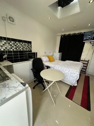 a room with two beds and a table and a kitchen at Luxury Ensuite Studio In Crayford Dartford Bexley London With Full Kitchen And Side Garden Alleyway Entrance in Slades Green