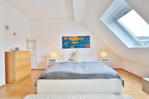 ein weißes Schlafzimmer mit einem Bett und einem Dachfenster in der Unterkunft Seepark Seepark Appartement 36 in Scharbeutz