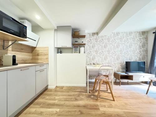 une cuisine avec des armoires blanches et une table et une chaise dans l'établissement Charmant T1 Neuf à Riom au Cœur de la Ville !N4, à Riom