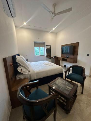 a bedroom with a bed and a chair and a tv at The Crown Prince in Greater Noida