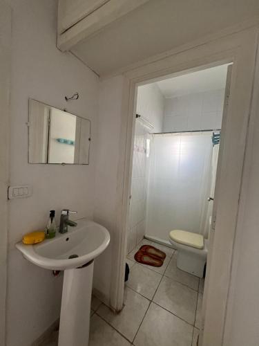 a white bathroom with a sink and a toilet at Like home in Bir Kassa