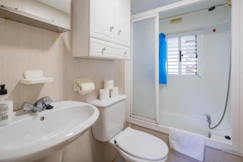 Un baño con un inodoro blanco y un lavabo. en Bungalow F, en Pontevedra