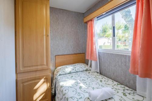 Un dormitorio pequeño con una cama y una ventana. en Bungalow F, en Pontevedra