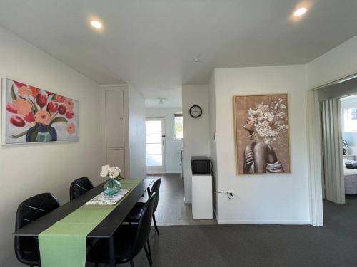 a dining room with a green table and black chairs at Cosy And Stylish Single Level 2 Bed Home Near CBD in Linwood
