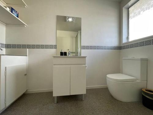 a white bathroom with a toilet and a mirror at Cosy And Stylish Single Level 2 Bed Home Near CBD in Linwood
