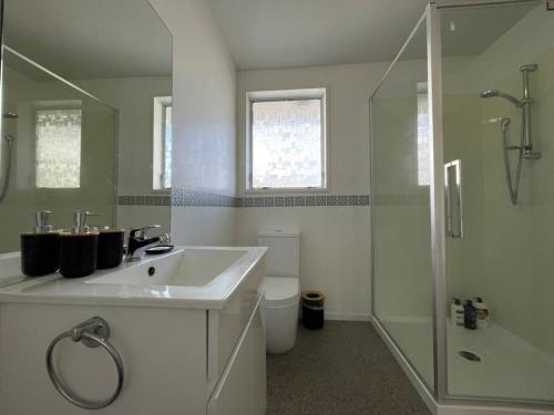 a white bathroom with a sink and a shower at Cosy And Stylish Single Level 2 Bed Home Near CBD in Linwood