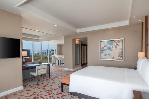 a bedroom with a large white bed and a desk and a desk at Solaire Resort Entertainment City in Manila