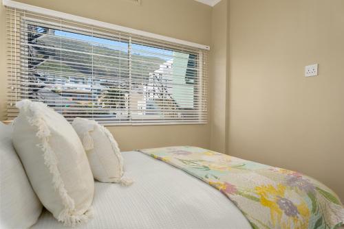 a bedroom with a bed with pillows and a window at Conifer Court 11 in Cape Town