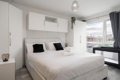 a white bedroom with a large white bed with black pillows at Pool Table - Coop Live Arena, Etihad & City stay in Manchester