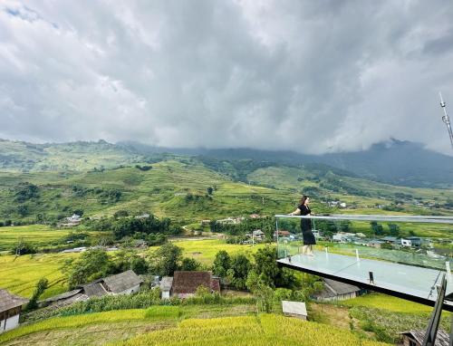 a woman standing on a balcony overlooking a valley at Boutique En Hotel Sapa in Sa Pa