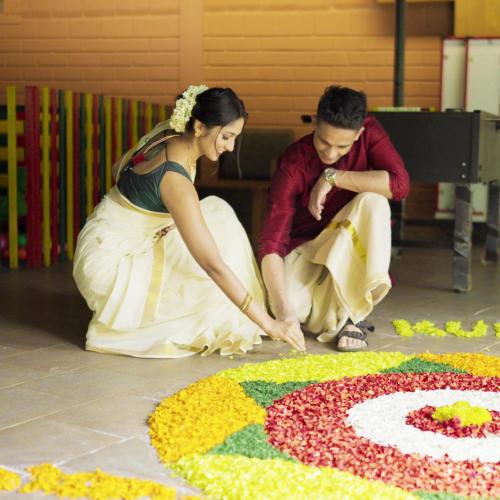 a man and a woman cutting into a flower rangoli at Kuruva Island Resort And Spa - By KABINI BREEZE in Mananthavady