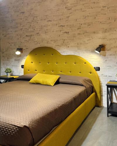 a large yellow bed in a bedroom with a brick wall at XiHouse Bed & Apartments - Iglesias in Iglesias