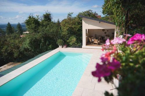 a swimming pool in front of a house with purple flowers at La Parenthèse, Les Gîtes de Montfaucon in Montfaucon
