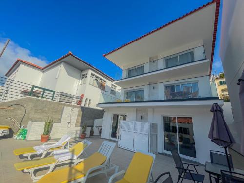 a patio with chairs and an umbrella in front of a building at Villa Supranee Paradise in Câmara de Lobos