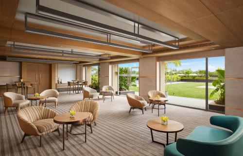 a lobby with tables and chairs and windows at Hyatt Place Aurangabad Airport in Aurangabad