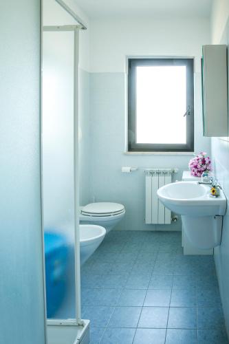 a bathroom with two sinks and a toilet and a window at Ficus Pineto Vacanza in Pineto