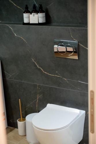 a bathroom with a white toilet and a black wall at VersusArtSuites in Serres
