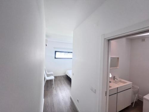 a white bathroom with a sink and a mirror at Vila Alivia in Nadadouro