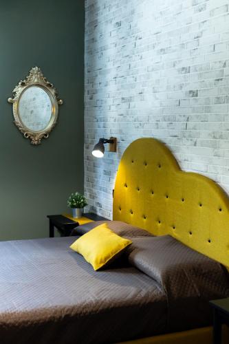 a bedroom with a yellow headboard and a brick wall at XiHouse Bed & Apartments - Iglesias in Iglesias
