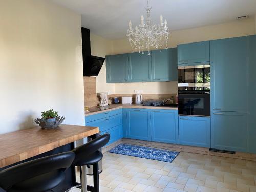 a kitchen with blue cabinets and a table and a chandelier at Au Gré des Souvenirs, gite 4 à 10 pers, clim, jacuzzi, loisirs in Château-la-Vallière