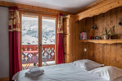 une chambre avec un lit et une grande fenêtre dans l'établissement Chalet Grand Mouflon, aux Gets