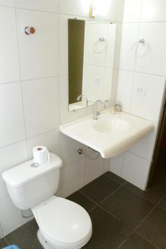 a white bathroom with a toilet and a sink at Requinte Hotel in Altamira