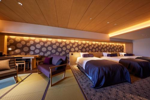a hotel room with two beds and a desk at Yumoto Konpira Onsen Hananoyu Kobaitei in Kotohira